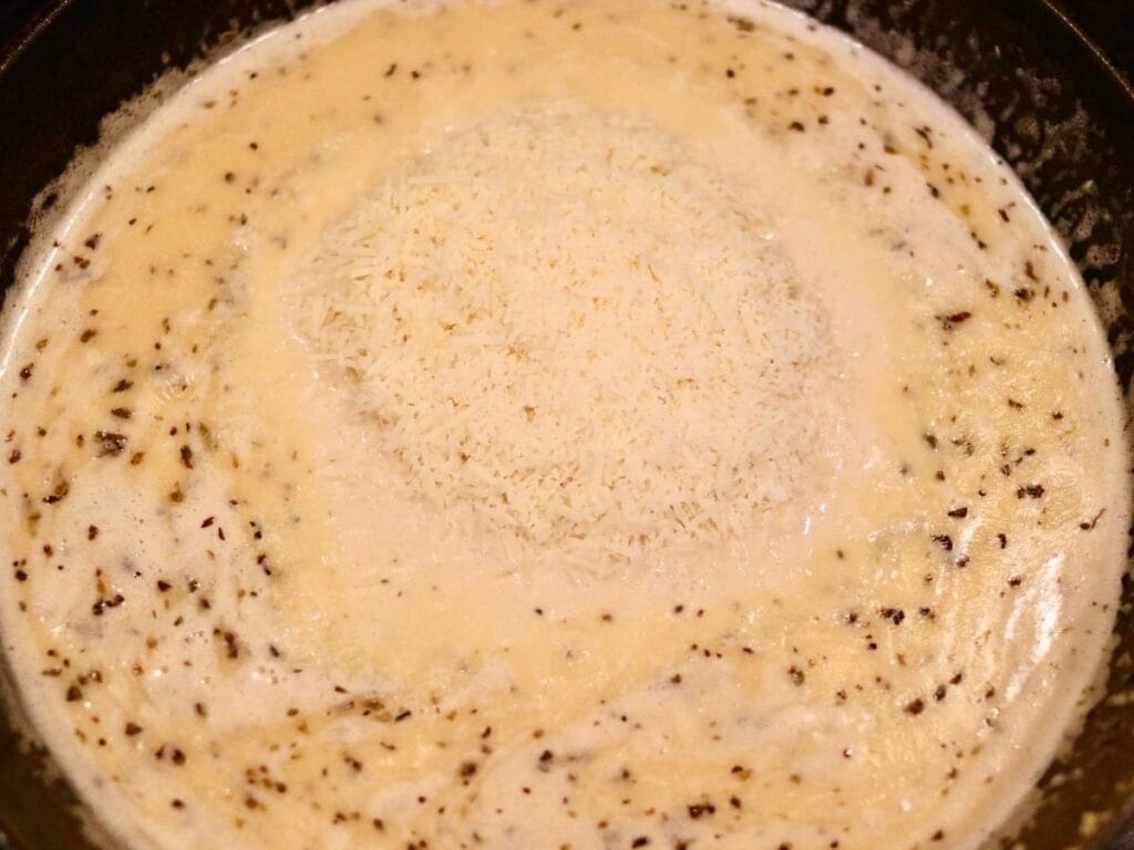 Adding parmesan cheese to sauce in a cast iron skillet