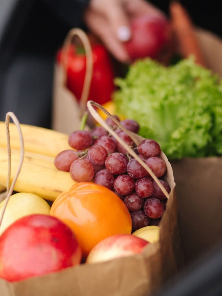 two paper grocery bags filled with variety of produce