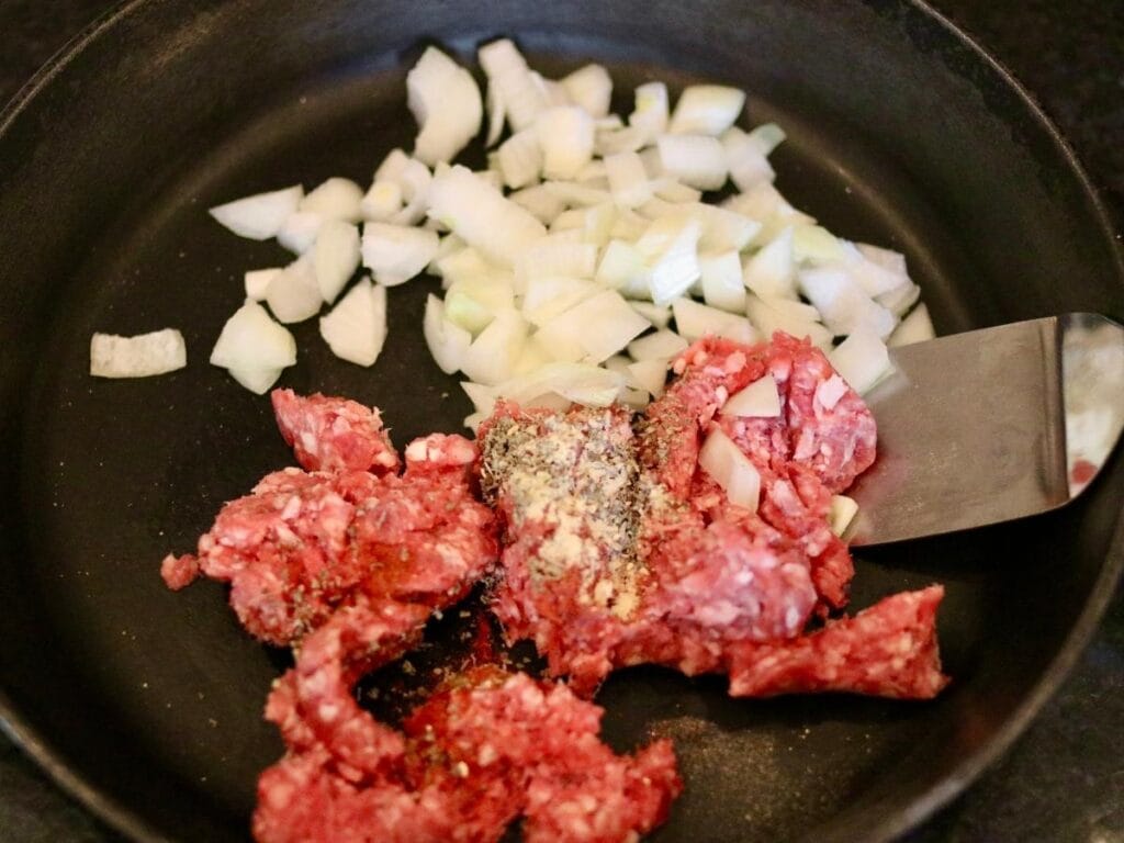 Browning ground beef and onions in a cast iron skillet