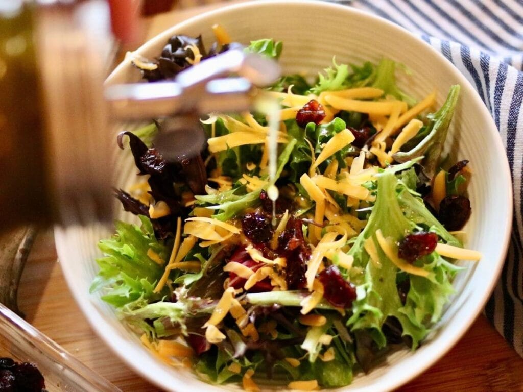 Drizzling Italian Vinaigrette over a fresh salad