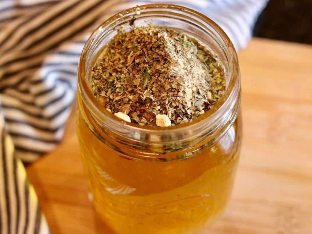 Adding spices to oil and vinegar in a mason jar