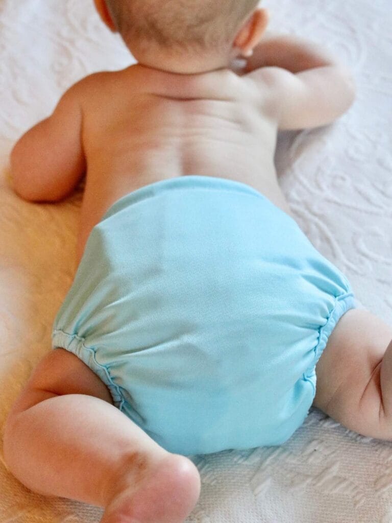 Baby laying on his belly wearing a cloth diaper.