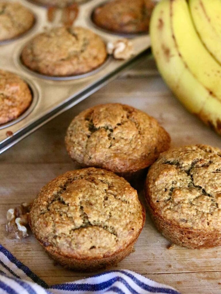 3 oat flour banana muffins beside muffin pan with muffins.