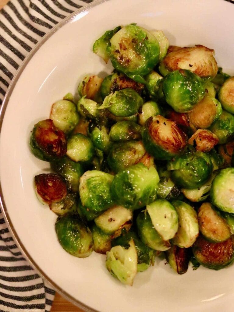 Closeup of stovetop Brussels sprouts in a bowl with a cloth napkin