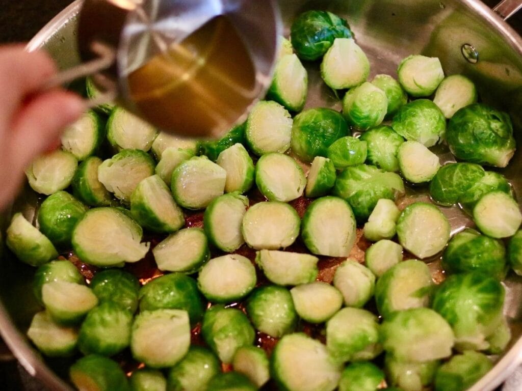 Pouring avocado oil over steamed Brussels sprouts