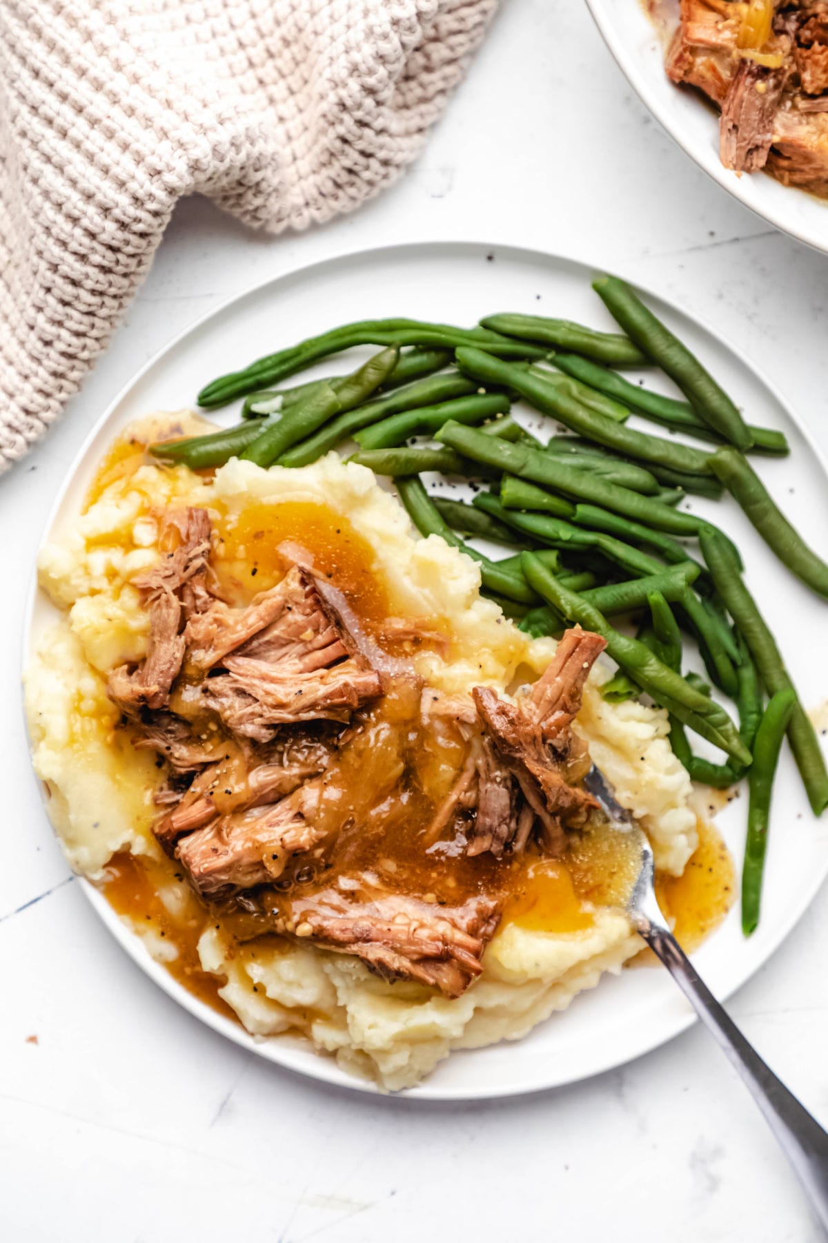 French onion pot roast over mashed potatoes on plate with green beans