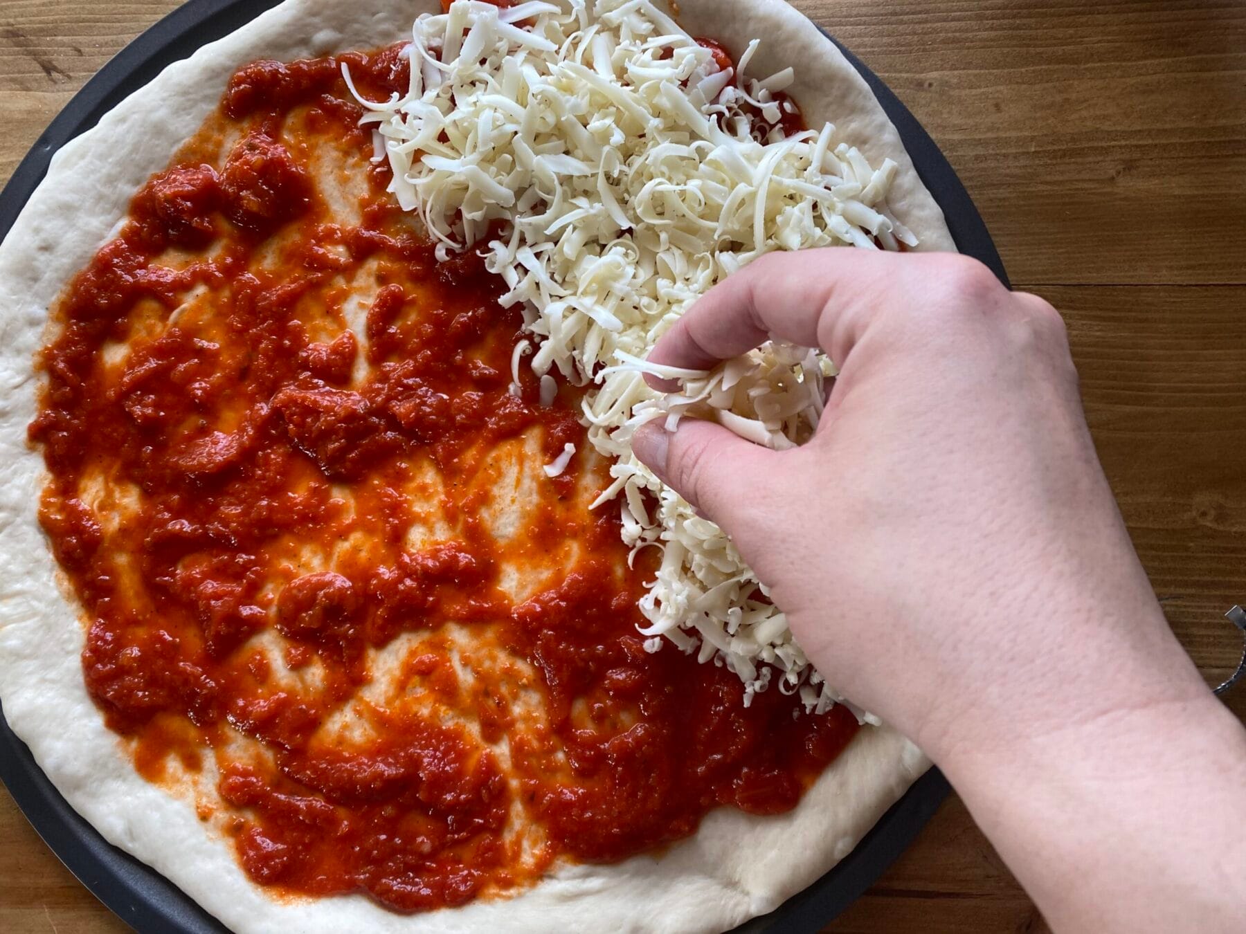 hand sprinkling cheese on pizza