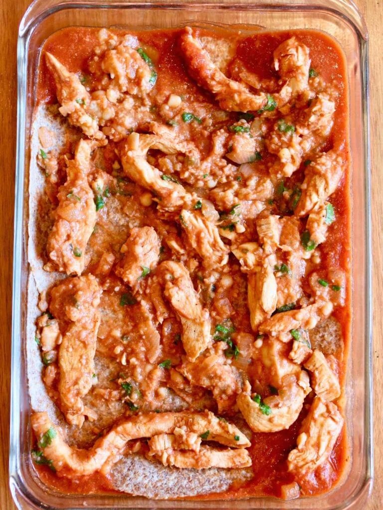 Layer of sliced chicken in a baking dish.