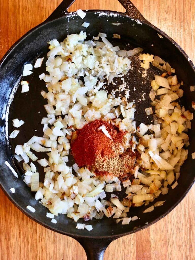 Adding spices to sautéed onions.