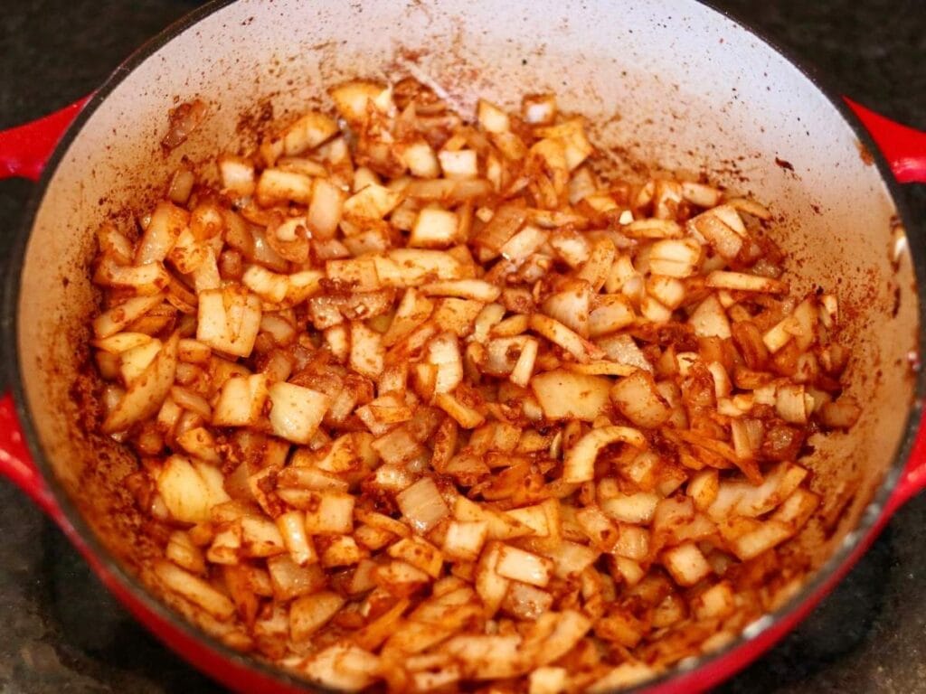 Onion and spice mixture in a dutch oven.