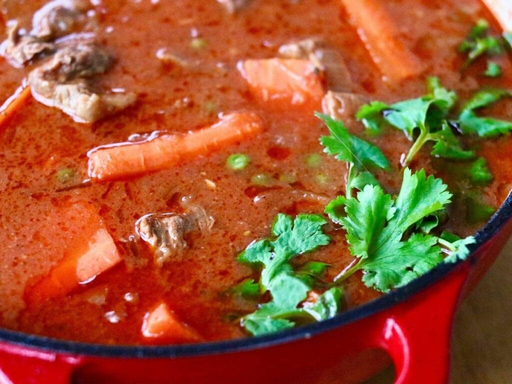 Indian beef curry in a Dutch oven with fresh cilantro.