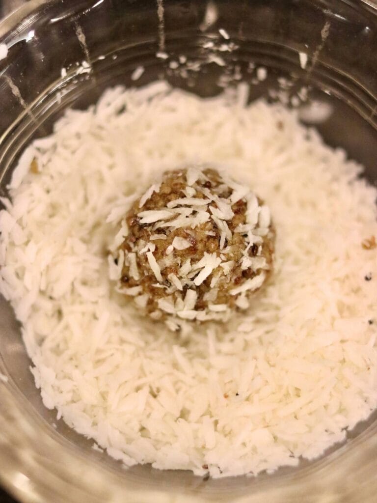 Rolling an oat-free protein ball with dates in shredded coconut.