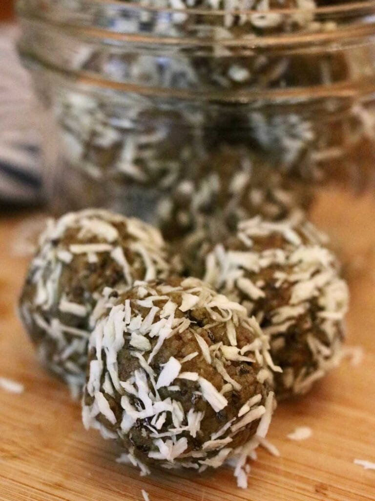 3 oat-free protein balls with dates beside a jar of protein balls.