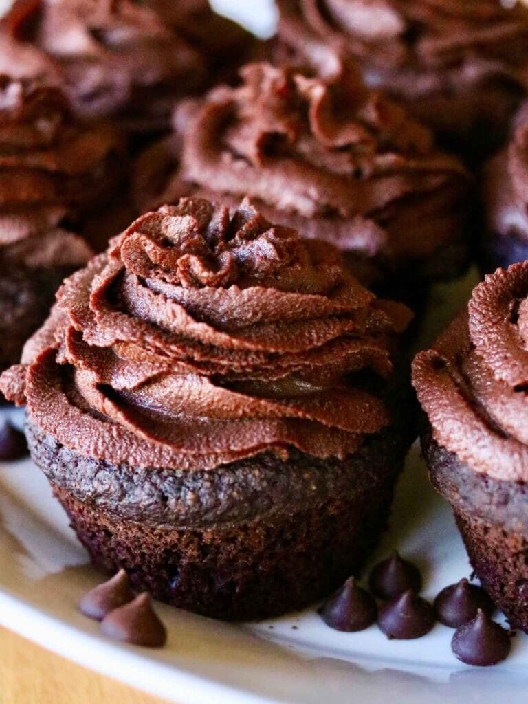 Frosted chocolate cupcake on a tray with more cupcakes.