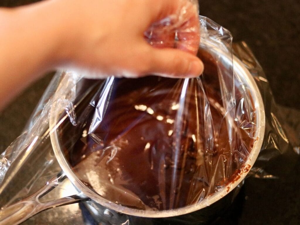 Covering a pan with melted chocolate mixture.