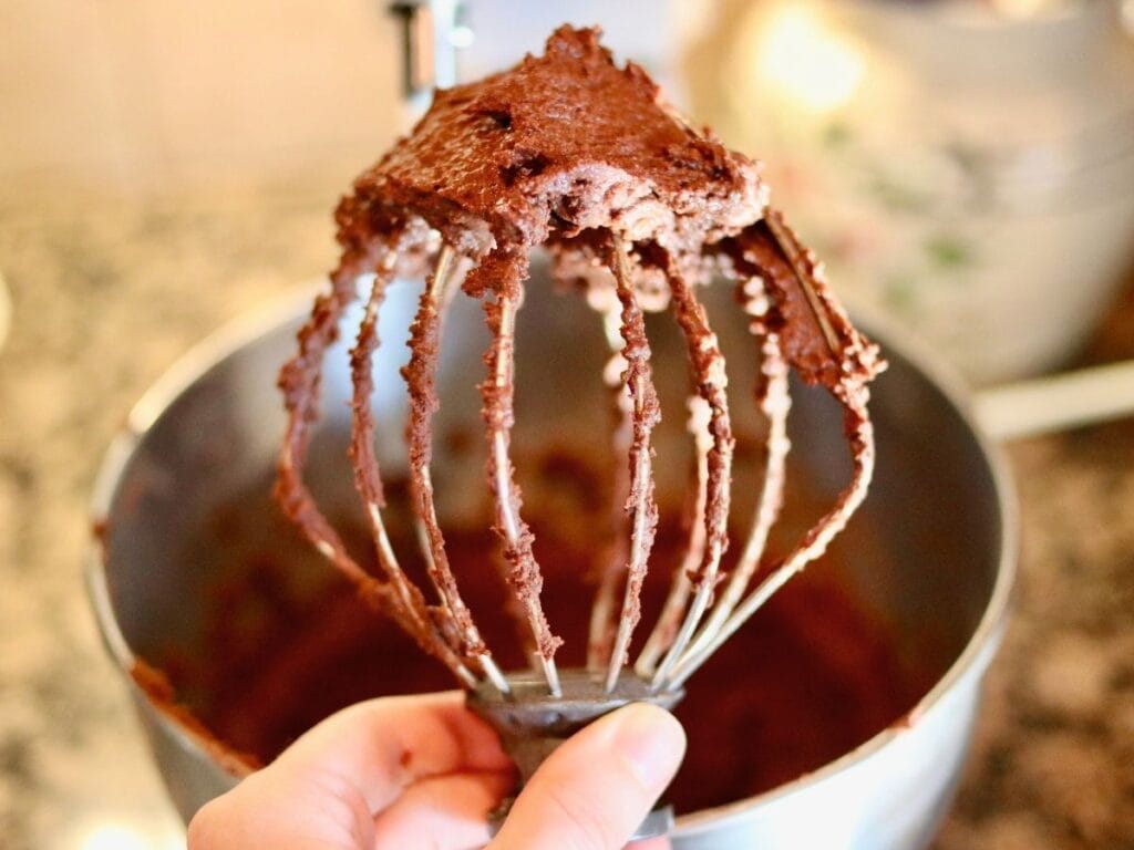 Chocolate frosting on a whisk attachment.