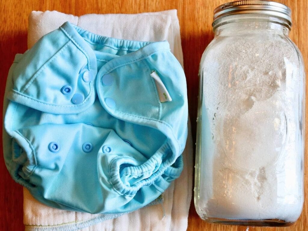 Jar of cloth diaper detergent beside clean cloth diapers.