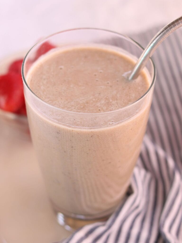 Ginger smoothie in a glass with a metal straw.