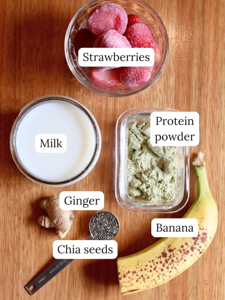 Ingredients for a ginger smoothie including strawberries, milk, ginger, and other foods.