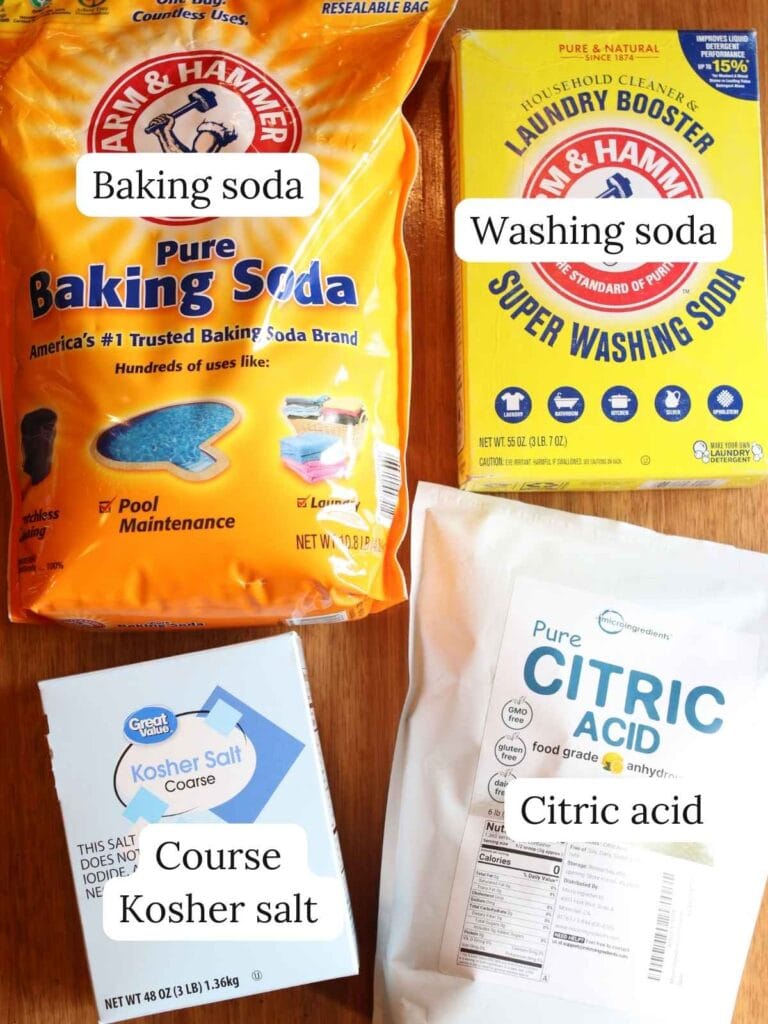 Baking soda, washing soda, citric acid and salt on a wood surface.