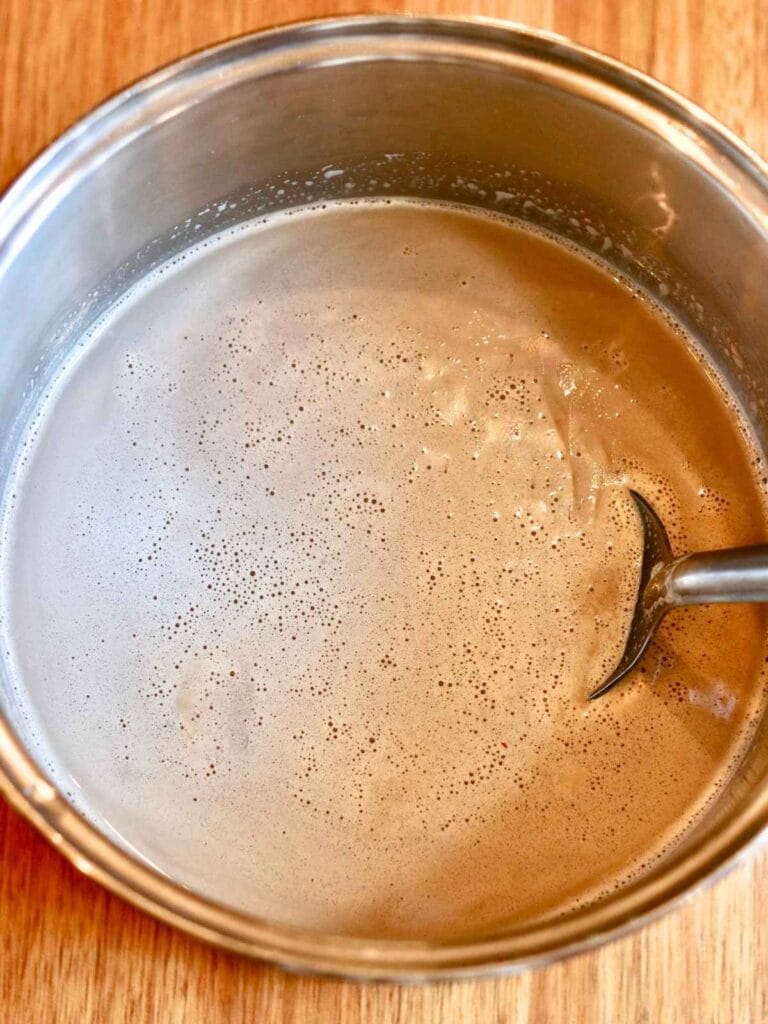 Stirring coconut sugar into hot milk.