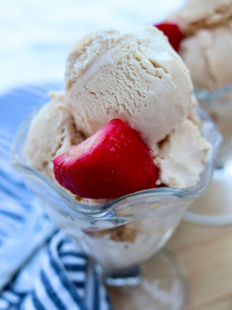 Closeup of bowl with homemade ice cream and half of a strawberry.