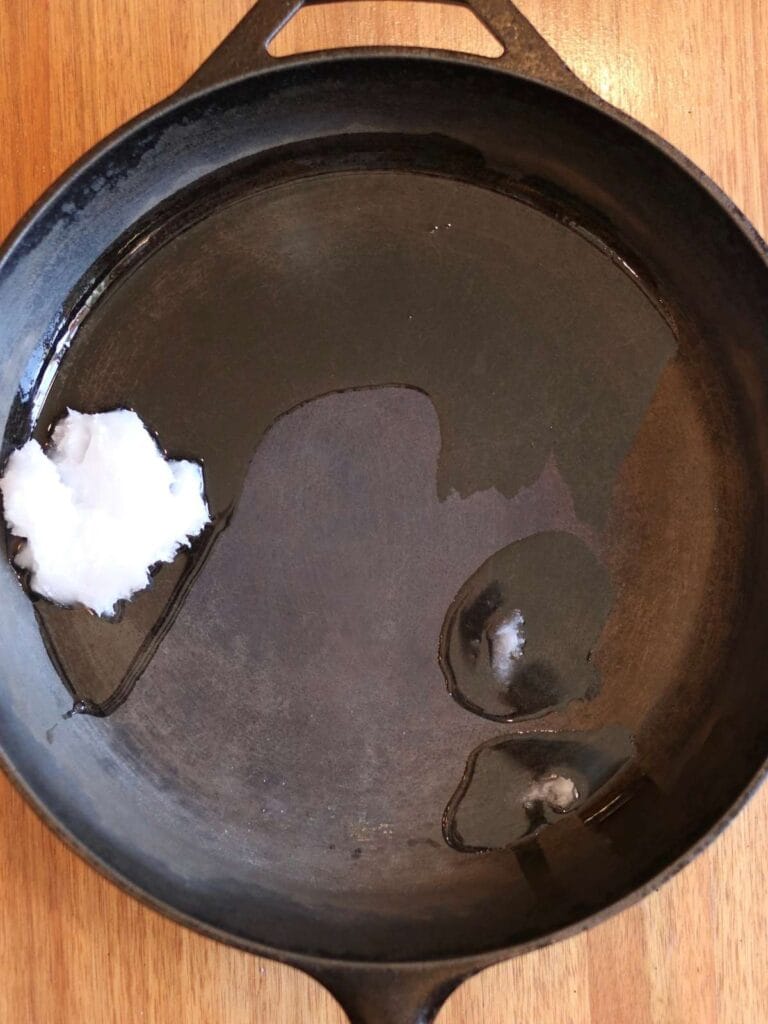 Coconut oil melting in a cast iron skillet.