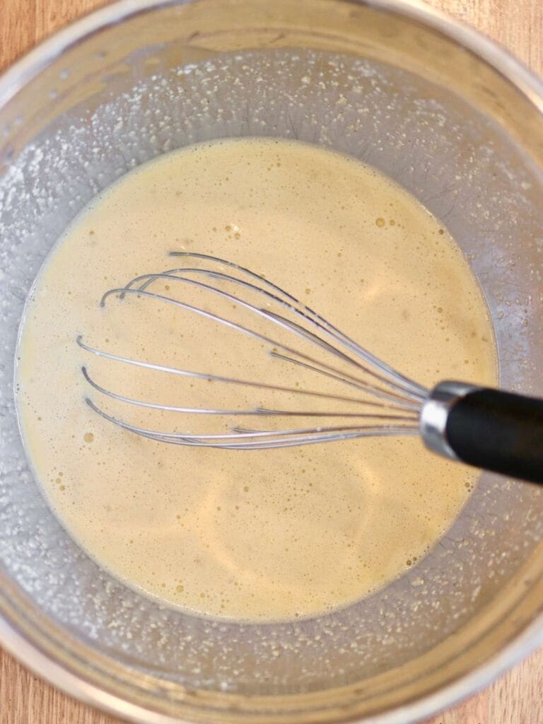 Whisking Dutch baby batter in a mixing bowl.