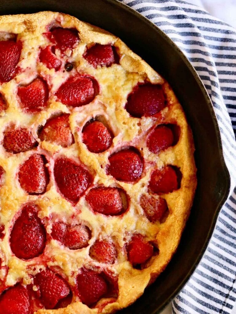 Closeup of strawberry Dutch baby in a cast iron skillet.