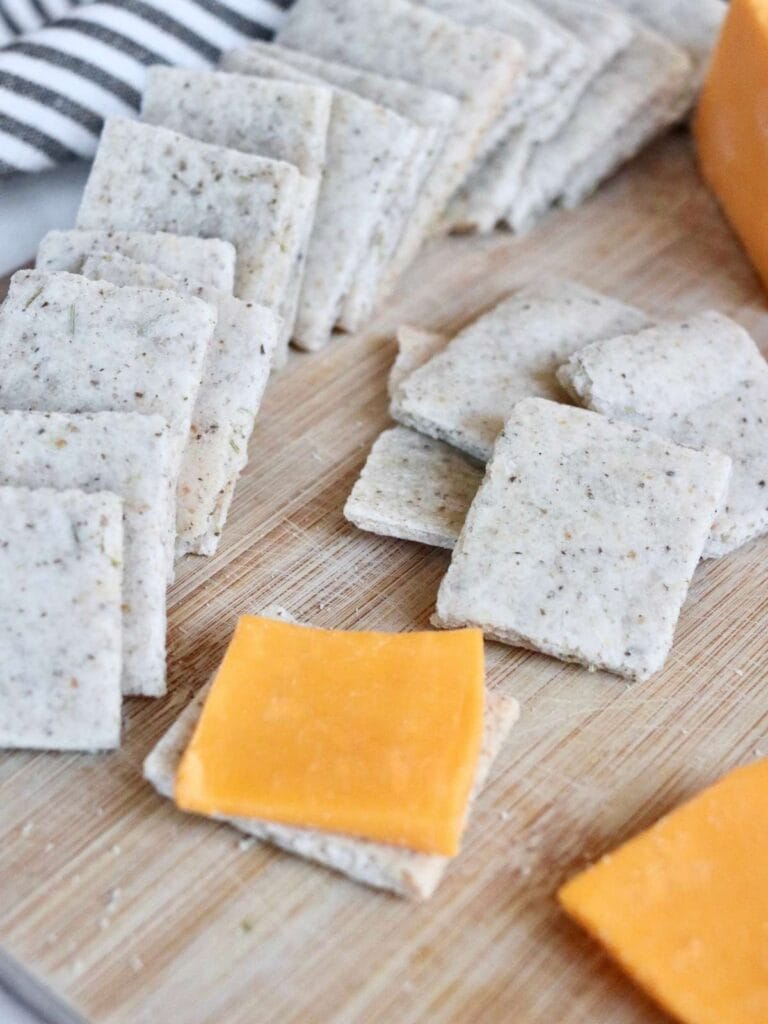Almond flour crackers and sliced cheese on a wooden board.