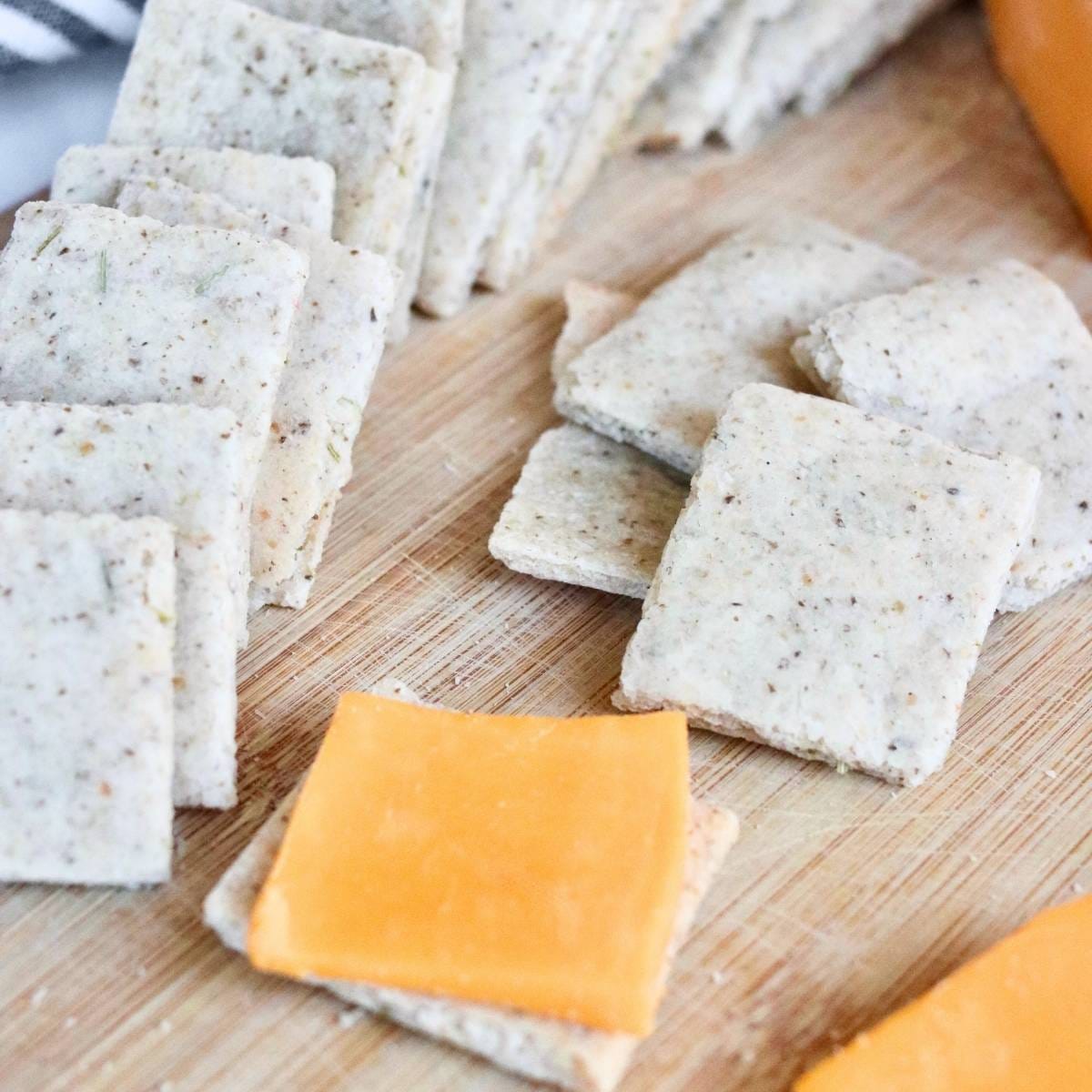 Almond flour crackers with slices of cheddar cheese on a wooden background.