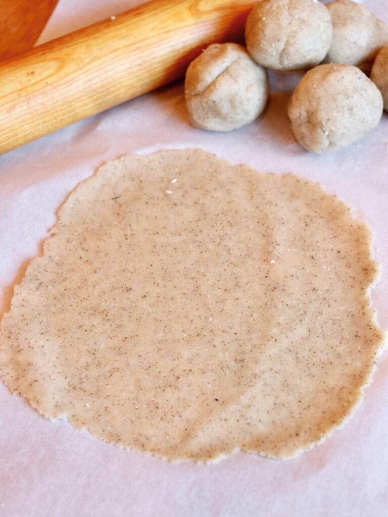 Rolled out tortilla with balls of dough and rolling pin.