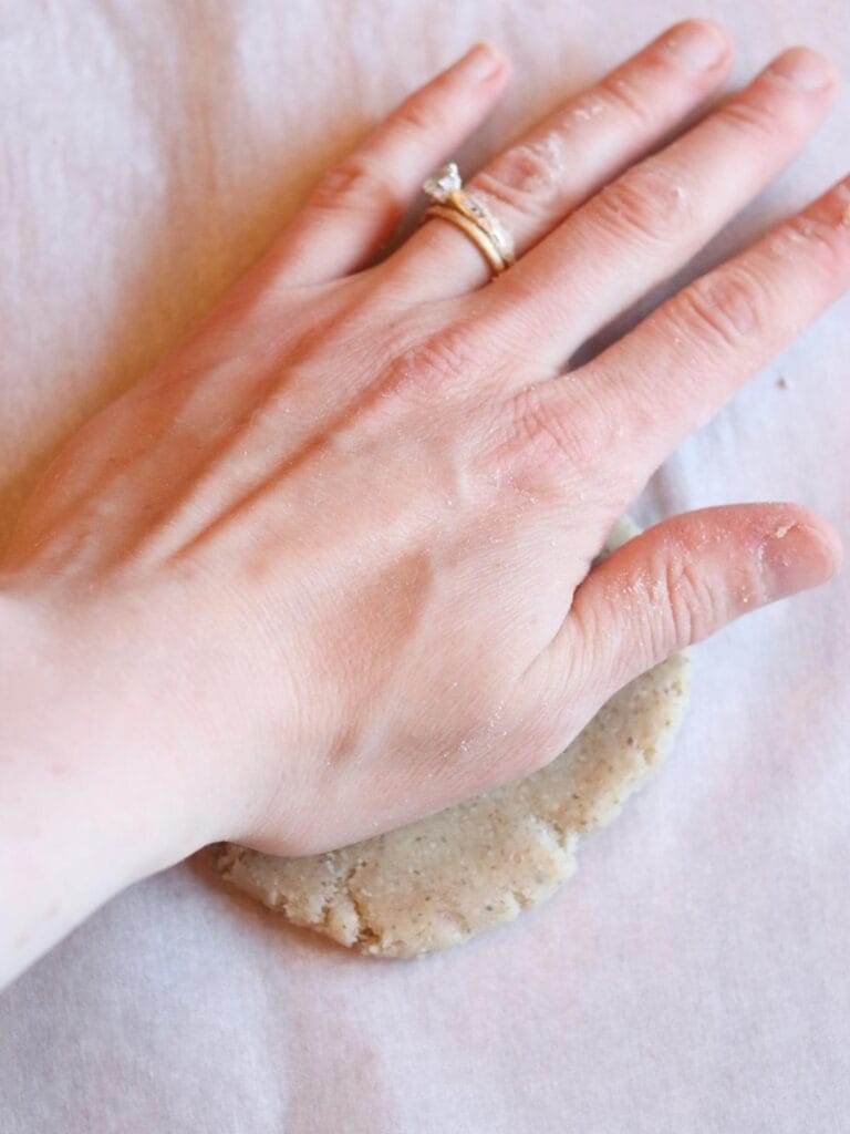 Hand pressing dough into circle.