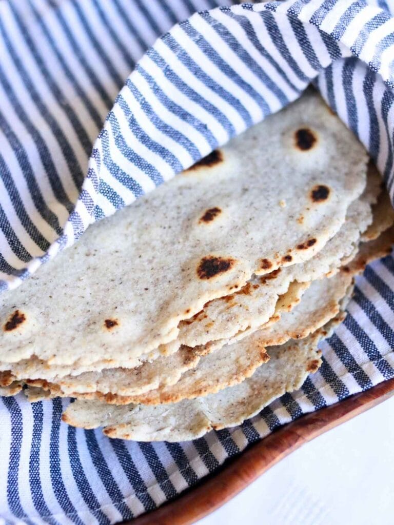 Stack of almond flour tortillas wrapped in a cloth in a bowl.