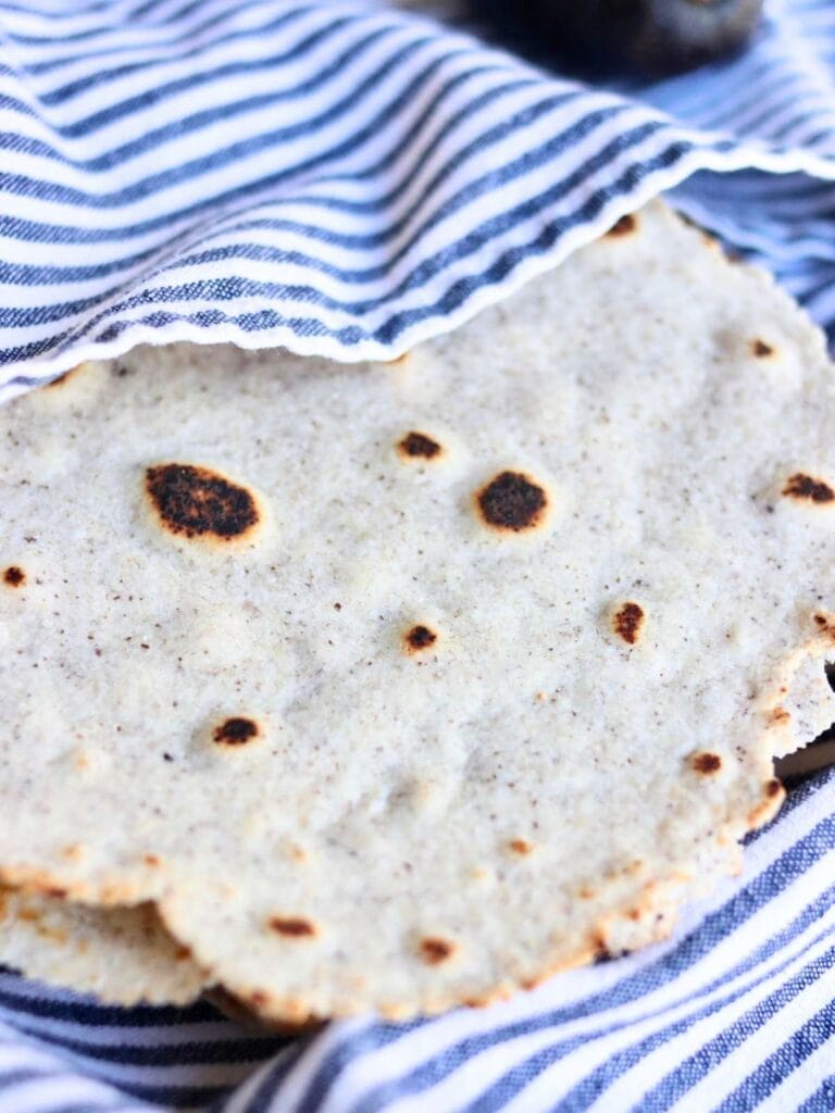 Stack of almond flour tortillas partially covered with a cloth.