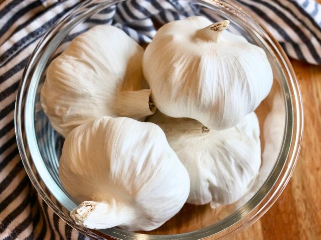 Four garlic bulbs in a bowl.