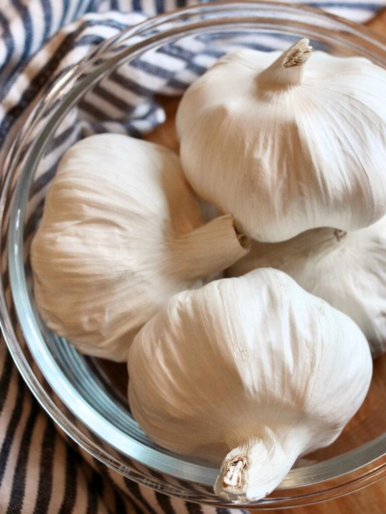 Bowl with four garlic bulbs.