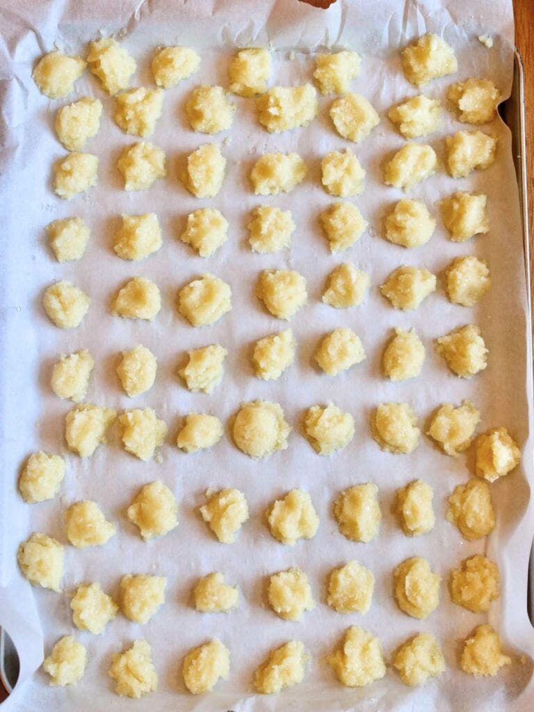 Portions of garlic paste on parchment paper on a baking sheet.