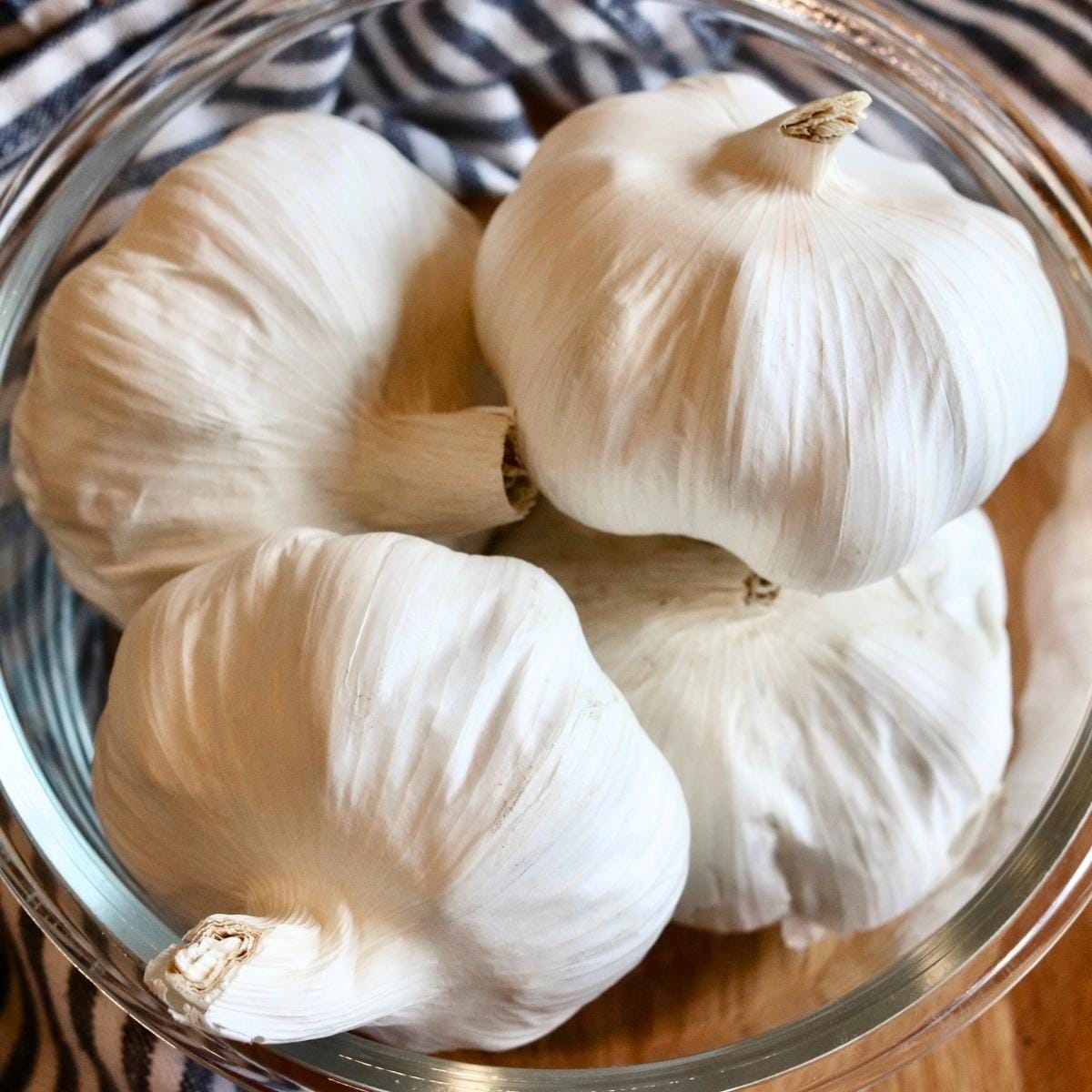 Closeup of garlic bulbs in a glass bowl.