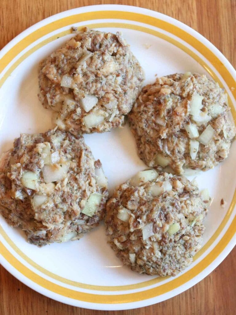 4 uncooked sardine fish cake patties on a plate.