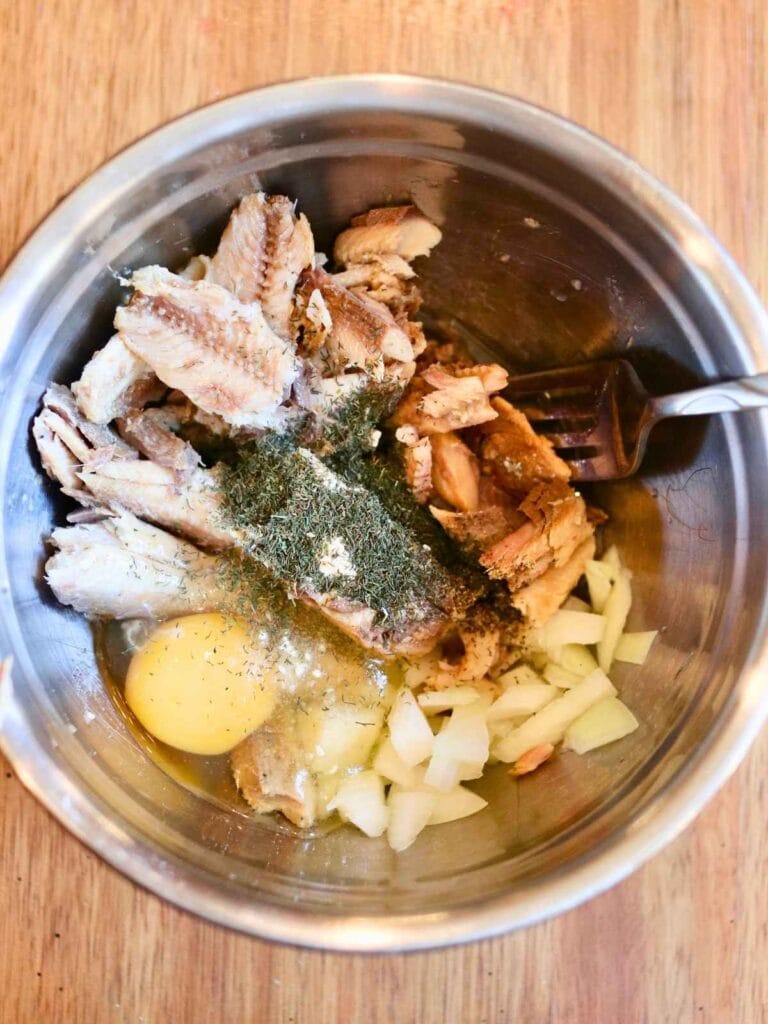 Ingredients for sardine fish cakes in a mixing bowl with a fork.
