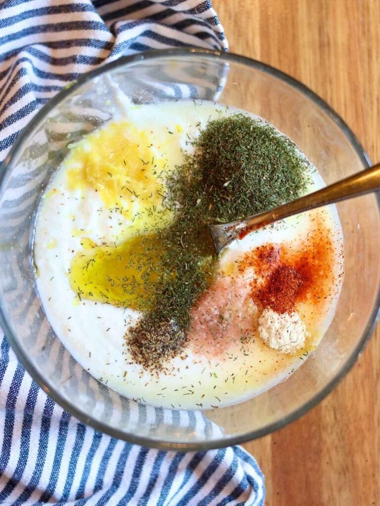 Mixing ingredients for yogurt dill sauce in a bowl.