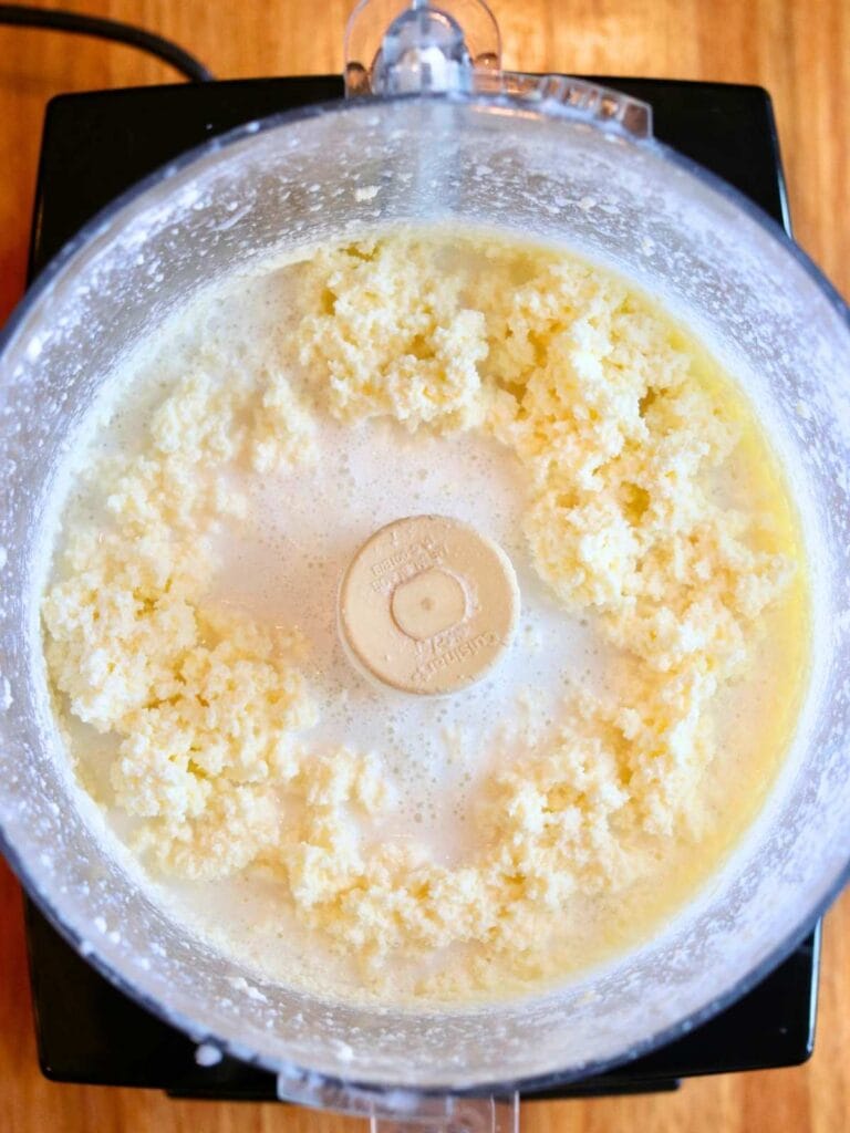Churning fresh cream in a food processor as it separates into butter curds and buttermilk — step in making butter from raw milk.