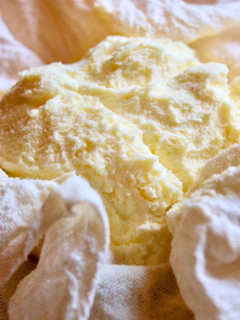 Freshly made raw milk butter resting in cheesecloth after churning in a food processor, ready for storage or use.