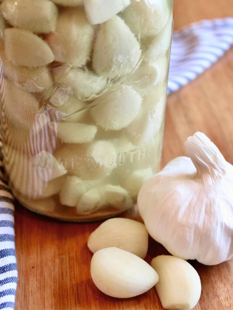 Fermented garlic with a fresh garlic bulb and a few cloves.