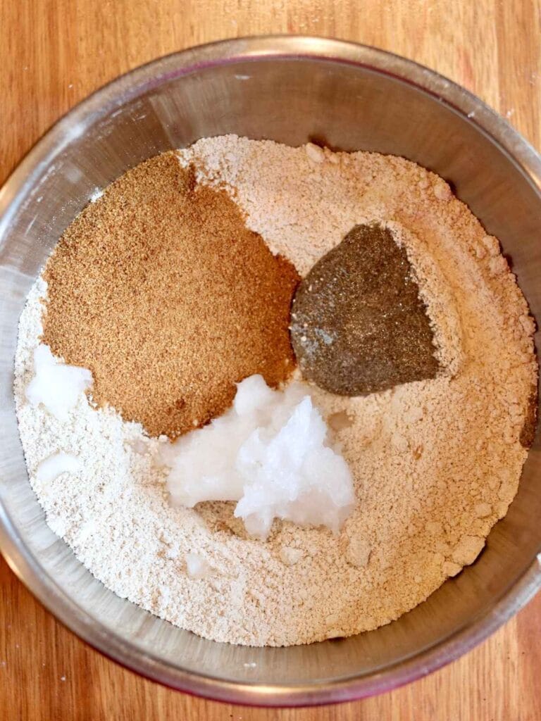 Adding coconut sugar, coconut oil, and chia egg to dry ingredients in a bowl.