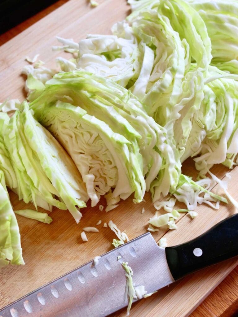 Slicing cabbage on a wooden cutting board.