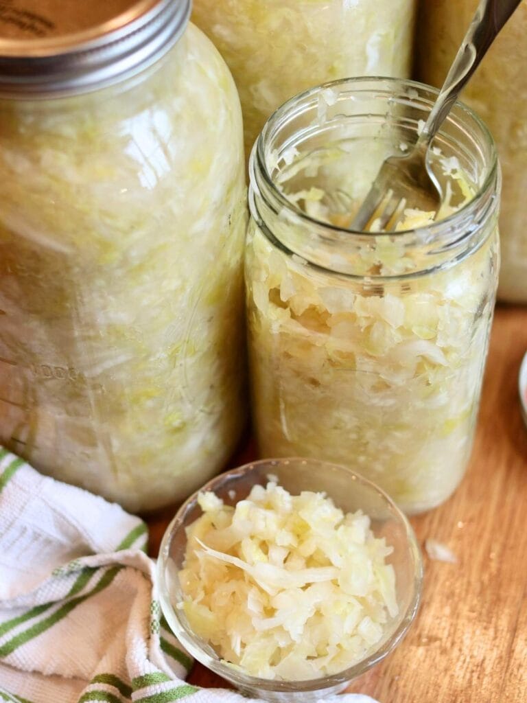An open jar of sauerkraut and a bowl with sauerkraut.