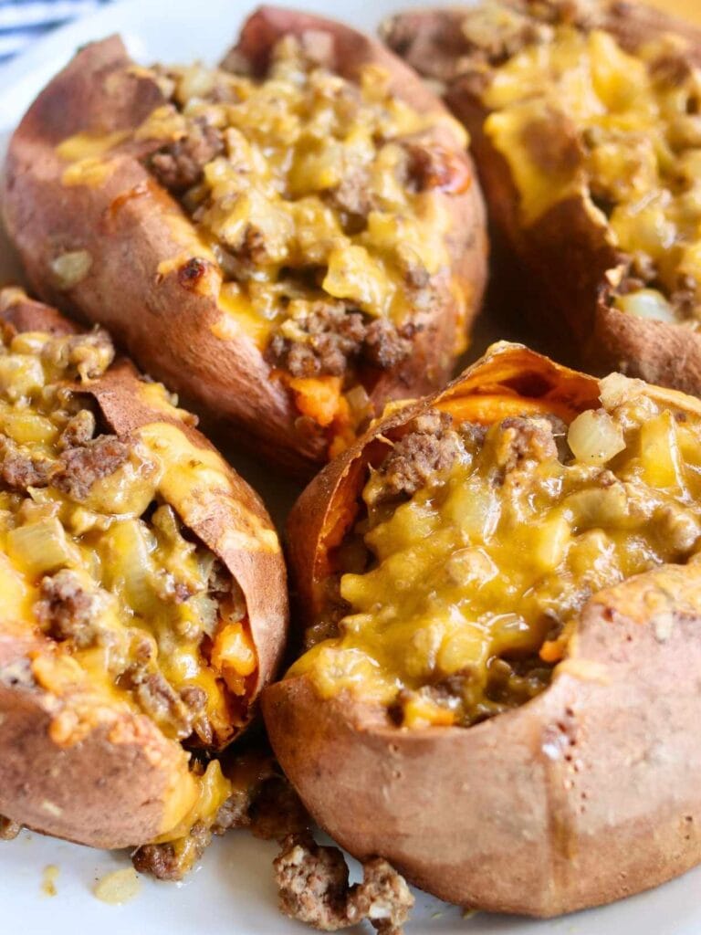 Closeup of 4 sweet potatoes and ground beef covered with cheese.
