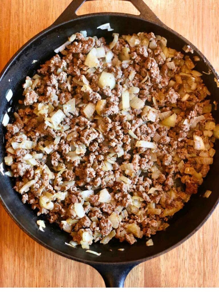Browned ground beef and onion in a skillet.